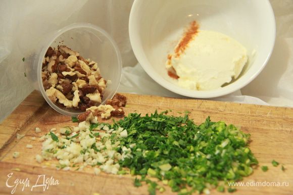 Подготовить ингредиенты для начинки: орехи, чеснок и зелень мелко порубить, в сливочный сыр добавить соль, перец чёрный и кайенский.