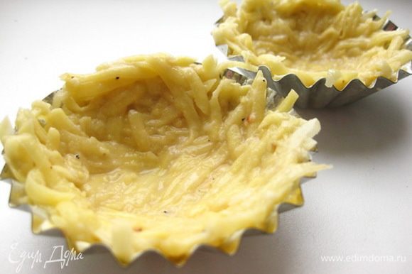 Формочки для кексов щедро смазать сливочным маслом и равномерно распределить по формочкам, чтобы получились картофельные кокотницы.