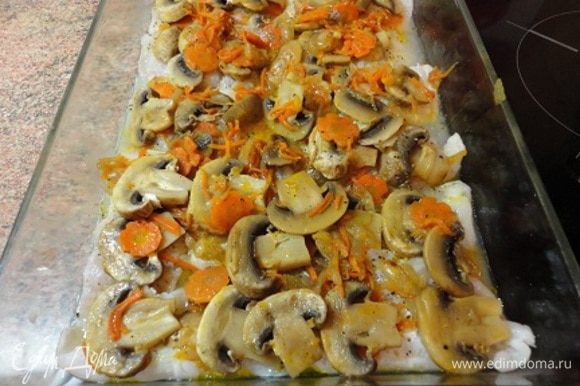 Сверху положить рыбное филе и грибы с оставшимися луком и морковью , влить 2-3 ложки рыбного бульона или просто горячей воды и запекать в разогретой духовке (200 градусов) 20 минут.