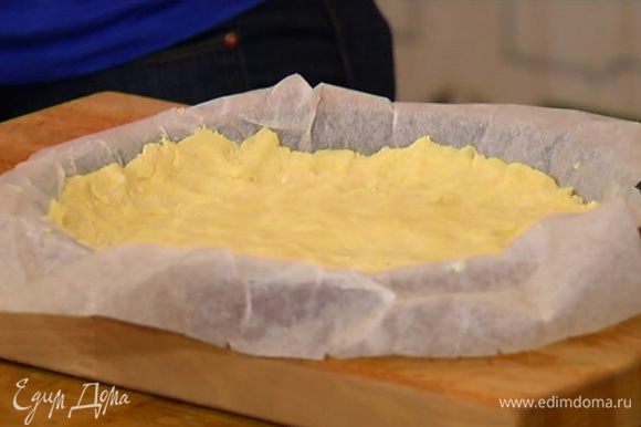 Оставшимся сливочным маслом смазать пекарскую бумагу, выстелить неглубокую форму для выпечки, выложить тесто, быстро распределить его по дну и бортикам формы и отправить в морозильник.