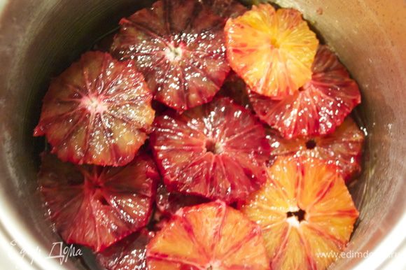 Выложить в сироп кружочки апельсинов и аккуратно перемешать, чтобы они покрылись сиропом.