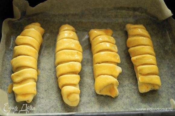 Выложить булочки на противень застеленный пергаментом и смазанный маслом, смазать булочки взбитым желтком.