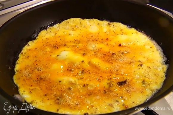 Разогреть в сковороде сливочное и оливковое масло, влить яйца со специями и готовить омлет в течение 2 минут.