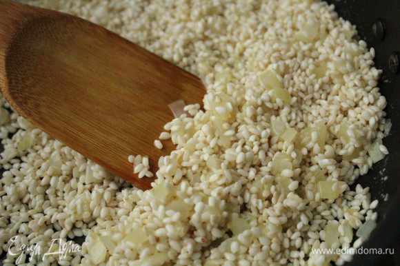 Добавить к луку рис и, постоянно помешивая, дать рису стать полупрозрачным.