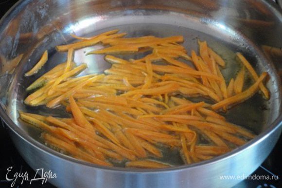 Морковь очистить и нарезать соломкой. Половину растительного масла разогреть в сковороде и обжарить морковь до мягкости.