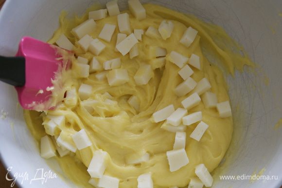 Положить в готовое тесто нарезанный кубиками сыр и перемешать.