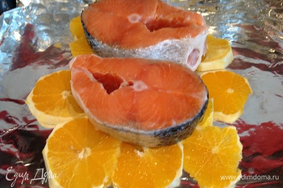 Выложите рыбу на апельсины, посолите.