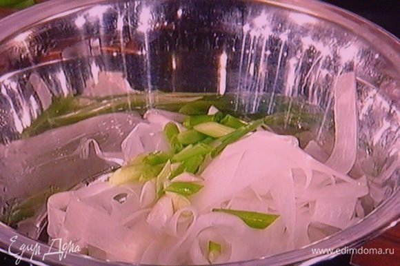 Для салата очистить дайкон и спец. ножичком для чистки овощей нарезать редьку на тонкие полоски. Добавить наискосок порезанный зелёный лук.