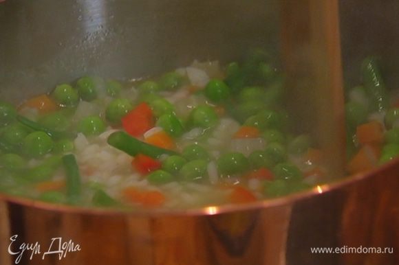 Добавить фасоль и горошек и варить еще 3–4 минуты до готовности риса и овощей, затем посолить и поперчить. Если суп получается слишком густым, влить еще немного горячей воды или бульона.