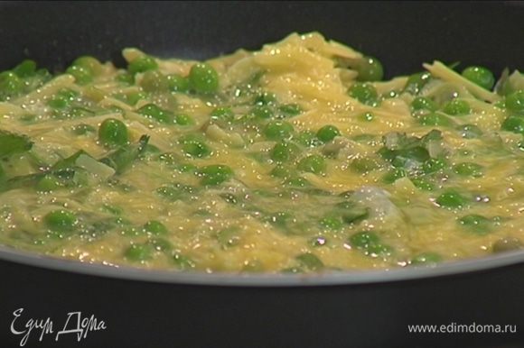 Яйца перемешать с зеленым горошком, натертым сыром и кинзой, а затем выложить в сковороду на картофель.