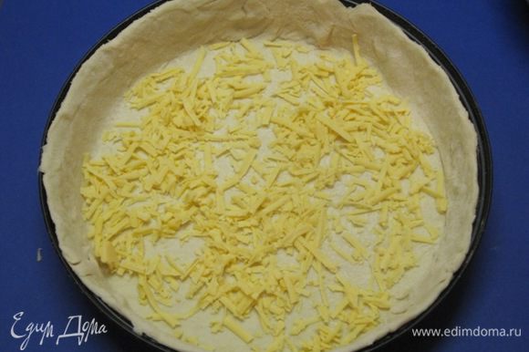 Сыр натереть на терке. Половину тертого сыра выложить на тесто.
