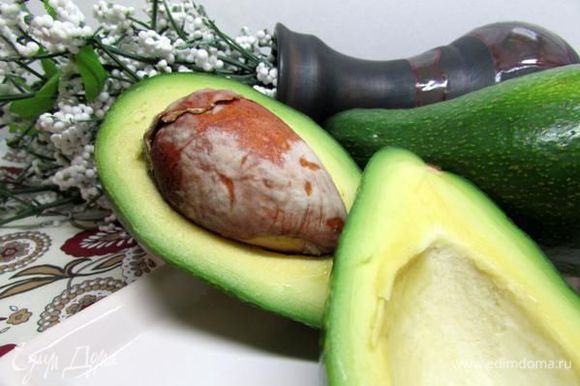 Разрежьте авокадо пополам, проверните половинки в разные стороны и разъедините.
