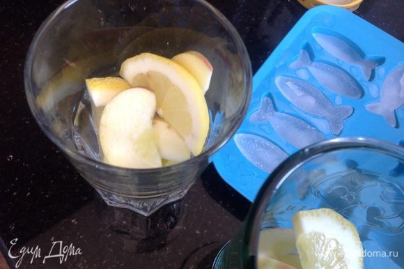 Положите в стаканы лед, дольки лимона и яблока...