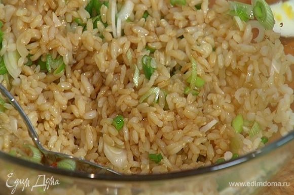 Готовый рис соединить с зеленым луком, полить оставшимся кунжутным маслом, рисовым уксусом, соевым соусом, посыпать подкопченным перцем чили и все перемешать.