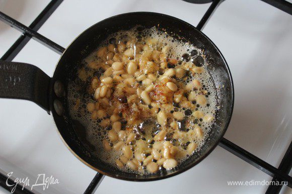 Сливочное масло растопить в сковороде, добавить размягчившийся чеснок и размять его. Добавить кедровые орешки и продолжать готовить все вместе, помешивая.