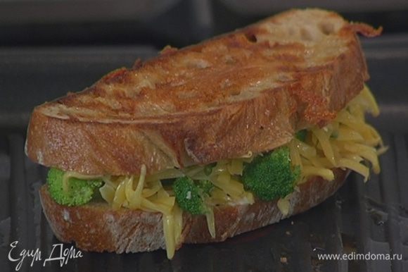 Разогреть в сковороде-гриль оливковое масло и, прижимая бутерброд к сковороде, обжаривать его с двух сторон до появления золотистых полосочек.