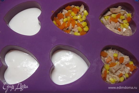 Достать из холодильника формочки и выложить кусочки куриного мяса, кукурузу и кубики моркови.