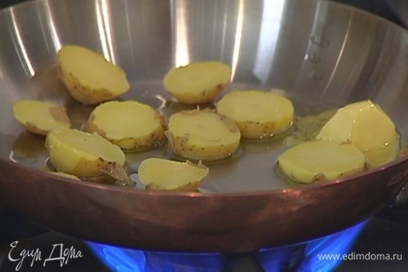 Разогреть в сковороде сливочное и оливковое масло и обжарить ломтики картофеля с двух сторон до золотистой корочки.
