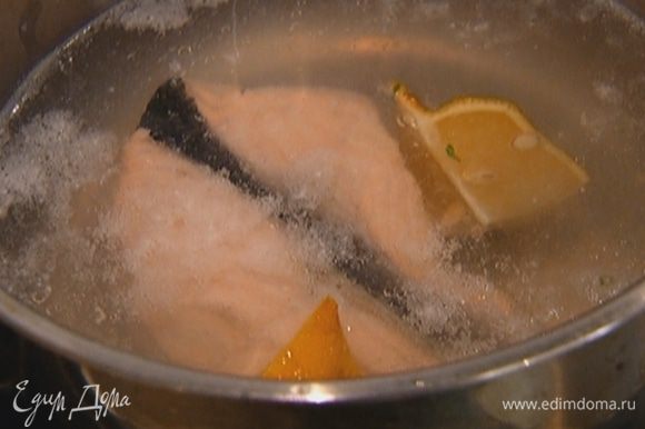 Стейк красной рыбы залить холодной водой, довести до кипения и варить 2 минуты. Выключить огонь, добавить в кастрюлю четвертинку лимона и, не сливая воду, дать рыбе остыть.