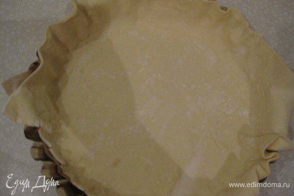 Слоеное тесто немного раскатываем, чтобы оно было толщиной 3 мм и выкладываем в форму. Обрезаем "свисающие" концы теста.