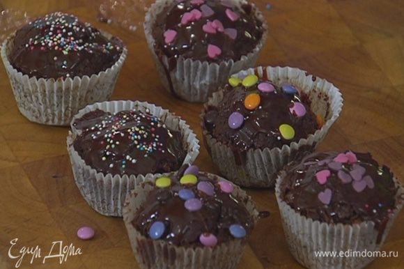Готовые капкейки полить шоколадной глазурью и украсить сахарными бусинками и сердечками.