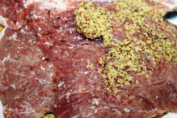 Посыпать мясо крупной солью, свежемолотым розовым перцем и смазать горчицей.