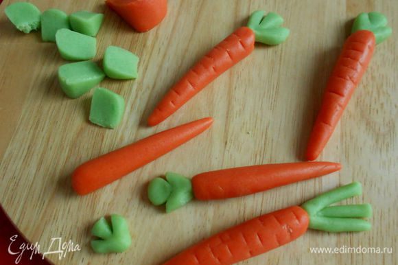 Разберите на сегменты и из оранжевых скатайте конусы, а из зеленых сделайте сплюснутые треугольники или скатайте жгутики. Неострым ножом сделайте произвольно поперечные отметины на морковках. Зеленые лепешечки разделите ножом на 3 сегмента в виде листочков. Если есть время и желание, листочки можно сделать более объемными. Конечно, у моркови нет таких листочков, но что-то зеленое должно быть на пироге!)