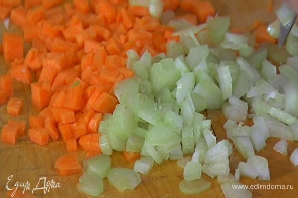 Порезать морковь и сельдерей маленькими кубиками, добавить в кастрюлю с луком, перемешать и обжаривать 3–5 минут на медленном огне.