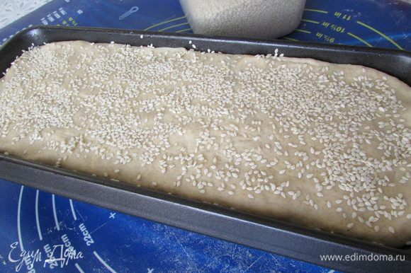 Смазать растительным маслом форму для выпекания хлеба. Выложить готовое тесто. Верх смазать растительным маслом и посыпать кунжутом. Накрыть салфеткой и оставить в теплом месте на 1 час для подъёма.