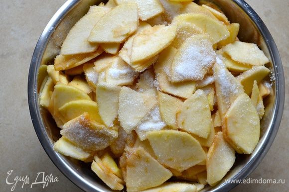 Яблоки подготовить заранее, за 1-2 часа до того, как Вы соберитесь печь пирог. Итак, яблоки лучше взять сорта ренет (или зеленые, типа Симиренко). Вымыть, очистить яблоки и нарезать на тонкие дольки толщиной примерно 2 мм. Выложить яблоки в миску и пересыпать сахаром. Осторожно перемешать, чтобы яблоки не поломались!