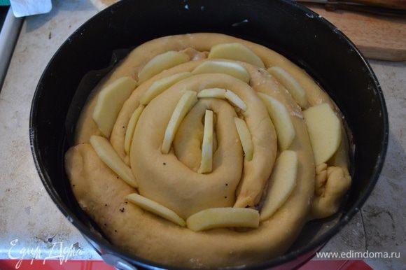 Вложить кусочки яблок между рулетами. Накрыть пирог полотенцем и поставить на расстойку на 20-30 минут.