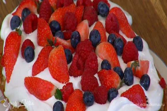 На остывший пирог выложить взбитые сливки, разровнять и украсить сверху свежими ягодами.