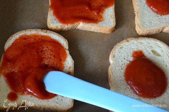 Духовку включить на 200 градусов. На противень застеленный пекарской бумагой выложите ломтики хлеба. Смажьте его томатным соусом (пассата).