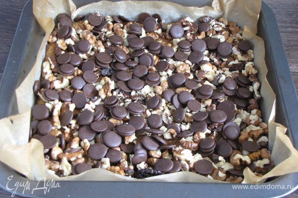 Шоколад порубить мелко, а орехи крупно. Я использовала готовые шоколадные кружочки. Посыпать готовый корж шоколадом и орехами.