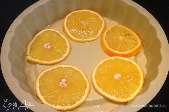 Один апельсин нарежьте кружочками и выложите на дно формы. Второй апельсин очистите и нарежьте небольшими ломтиками.