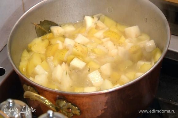 Когда лук станет мягким, добавить в кастрюлю яблоко, залить все горячим бульоном так, чтобы овощи были покрыты, снова накрыть крышкой и варить еще минут 10‒12, до готовности сельдерея и картофеля (если нужно, подлить еще бульона).