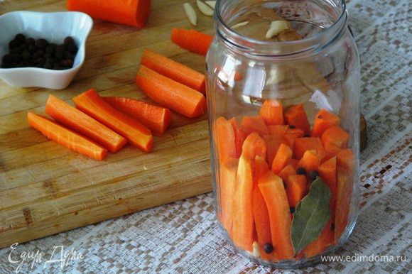 В подготовленную чистую банку начинаем плотно укладывать морковь, добавляя чеснок и специи (у меня лавровый лист, душистый перец, 2 гвоздички).