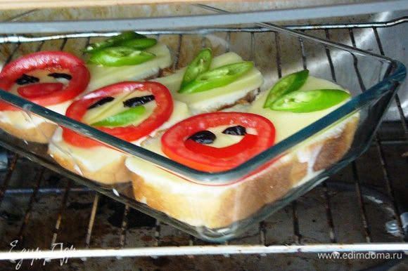Выложить на сыр помидоры и перец в виде улыбающейся рожицы. Разместить форму с бутербродами в разогретую до 200 градусов духовку.