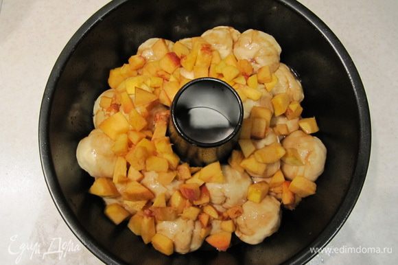 А затем выложить кусочки персика. Накрыть форму пленкой и отправить в теплое место на повторную расстойку на 35 минут.