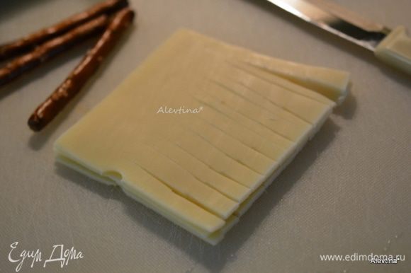 Сыр швейцарский пластинками нарезать полосками, оставив несколько сантиметров от начала.