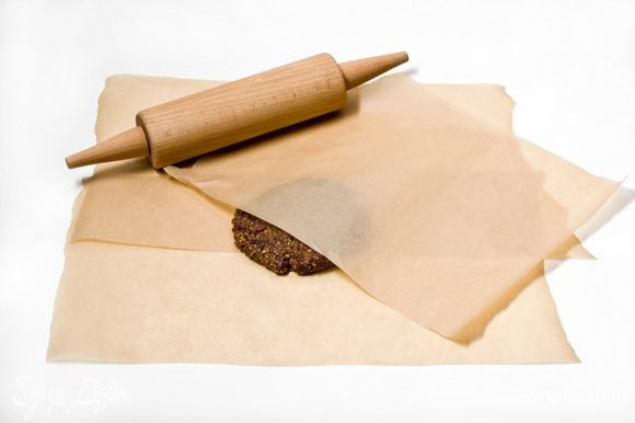 Выложить ореховую смесь между двумя листами пергаментной бумаги и раскатать пласт теста, толщиной 1,5 см.