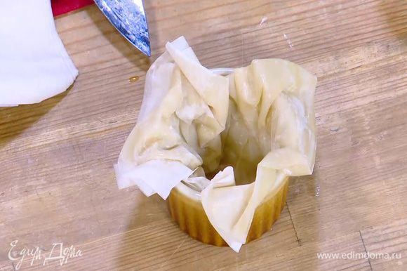 Поместить сложенное тесто фило в небольшие керамические формы так, чтобы края теста слегка свешивались.