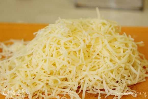 Сыр натереть на мелкой терке. Половину сыра добавить в горячий соус и хорошенько перемешать.