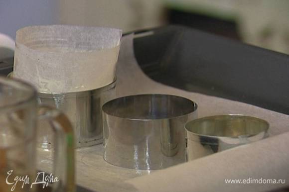 Выстелить противень бумагой для выпечки, смазать ее сливочным маслом, поставить на нее кольца для выпечки и выстелить их изнутри бумагой для выпечки, смазанной сливочным маслом.