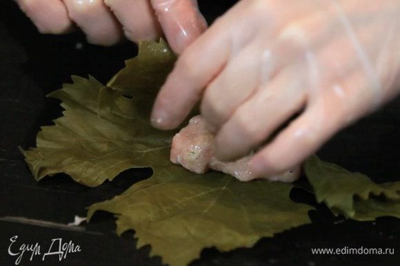 Выложить 1 ст. л. ложки начинки в центр виноградного листа (лист кладётся глянцевой стороной вниз). Накрываем начинку нижней частью листа.