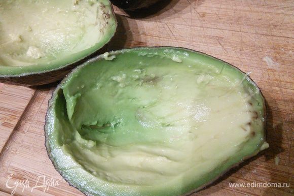 Авокадо вымыть, обсушить, разрезать наполовину, извлечь косточку. Авокадо должен быть спелым. Ложкой вынуть до 2/3 мякоти. Мякоть нарезать и аккуратно вмешать в остальной салат.