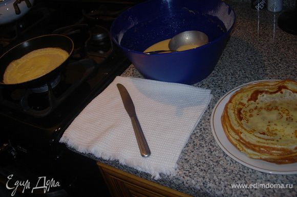 Дайте тесту несколько минут отдохнуть, а за это время подготовьте рабочее место. Понадобиться антипригарная сковорода с ручкой, половник, нож с тупым концом, плоская тарелка или стеклянная разделочная доска. Разогрейте хорошо сковороду, затем убавьте огонь в положение "чуть меньше среднего", если сомневаетесь, то для первого блина предварительно смажьте сковороду растительным маслом или сливочным маслом наколотым на вилку. Половником еще раз слегка перемешайте тесто, зачерпните нужное количество, ориентируясь на размер сковороды, поднимите сковороду с плиты и навесу влейте тесто на сковороду. Наклоняя сковороду в разные стороны заполните дно, кладите ее обратно на плиту, но далеко не уходите. Блинчики жарятся быстро. Как только край подрумянился поддеть его ножом и переверните блинчик аккуратно держа пальцами обеих рук. Постарайтесь не обжечься. Обжаривать со второй стороны нужно еще меньше времени, чем с первой. Снимайте с огня на тарелку (можно прикрыть широкой крышкой или миской, так блины получатся еще нежнее и не будет сухих краев) и продолжайте жарить.