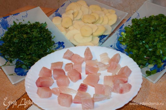 Филе рыбы вымыть, обсушить и нарезать на небольшие кубики. Зеленый лук, укроп, петрушку вымыть и мелко нарезать. Картофель вымыть, очистить и нарезать тонкими кружочками.
