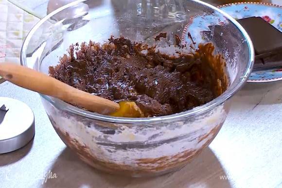 В яично-сахарную смесь добавить арахисовое масло, муку с разрыхлителем и измельченные орехи, все перемешать, затем влить растопленный шоколад и вымешать тесто.