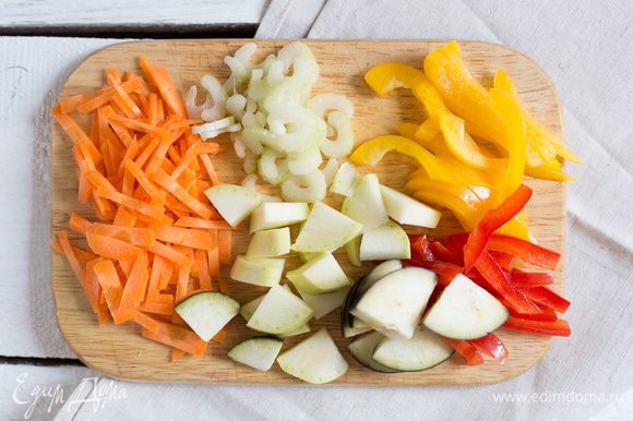 Разогрейте духовку до 200°C. Крупно нарежьте кабачок, баклажан и морковь. Порубите стебли сельдерея и тонко нарежьте красный и желтый перец.